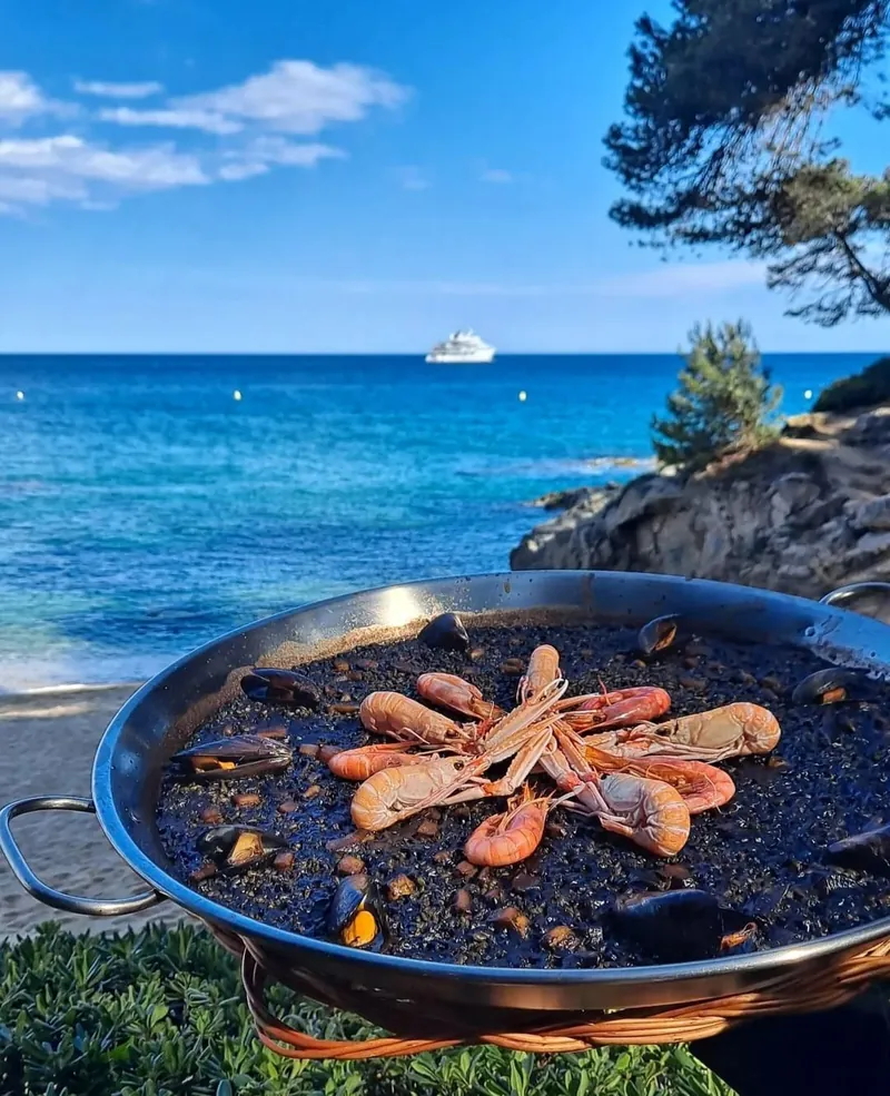 Arroz negro recién hecho con el mar de la cala detrás