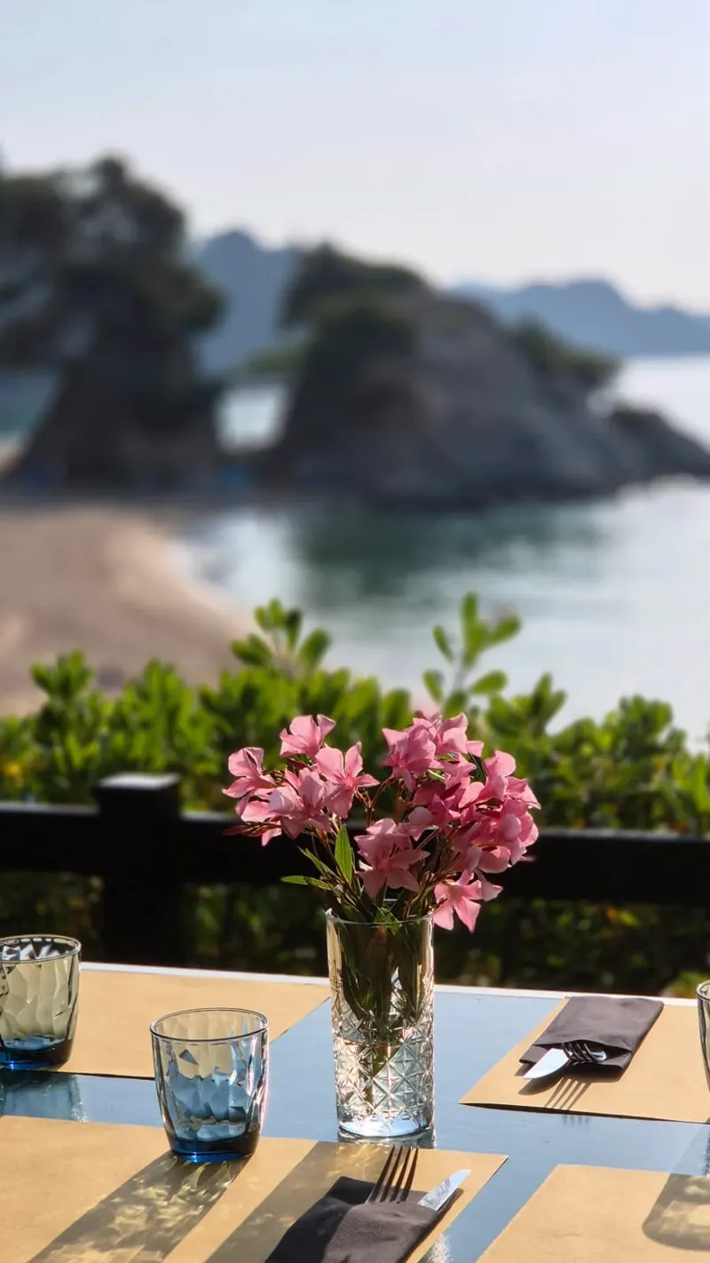 Mesa preparada con flores frente a la cala en el Xiringuito Cala Treumal